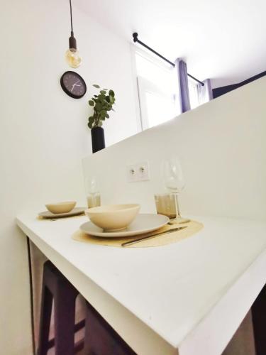 - un comptoir blanc avec deux assiettes et des verres dans l'établissement L'alcôve (Centre - Gare - Commerces), à Lens