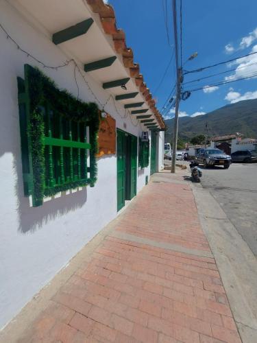 een gebouw met groene ramen en een bakstenen stoep bij POSADA CASA MIA in Villa de Leyva