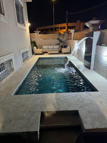 a swimming pool with a fountain in the middle of a house at Villa Rêve d'Agadir - Piscine Founty - Parking - Confort et Spacieuse villa familliale privée in Agadir