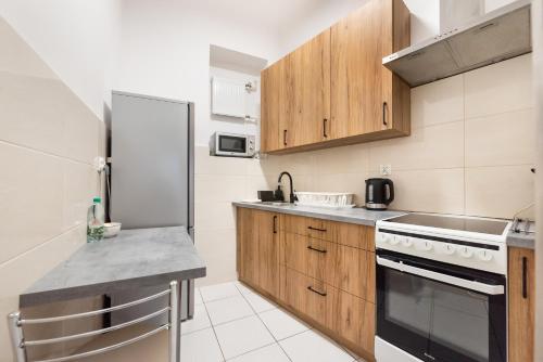 a kitchen with wooden cabinets and a refrigerator at Old Town 5-Bedroom Apartment in Warsaw