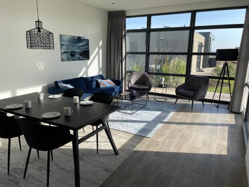 a living room with a blue couch and a table at Enkhuizer Strand Chalet Hafenplätzchen mit Zaun Haus Nr 244 in Enkhuizen
