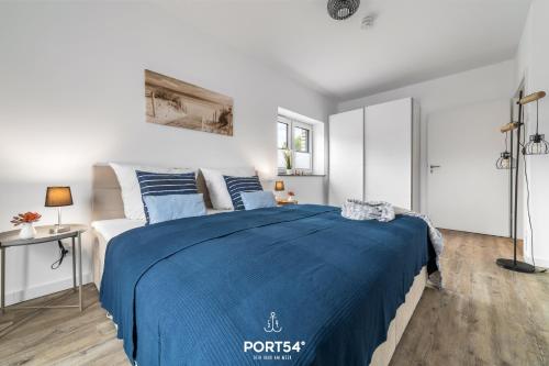 ein Schlafzimmer mit einem blauen Bett in einem weißen Zimmer in der Unterkunft Ferienwohnung Salzbrise Fehmarn in Fehmarn