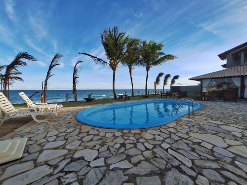 una piscina con palmeras y el océano en Condomínio à Beira Mar - Barra de São Miguel - AL, en Barra de São Miguel