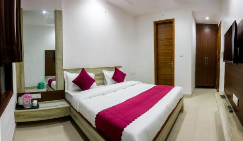 een slaapkamer met een groot wit bed met rode kussens bij Hotel NEU-NEST in Rishīkesh