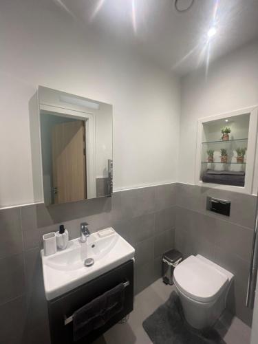 a bathroom with a sink and a toilet and a mirror at London Heathrow Airport Apartment Voyager House Terminal 12345 - EV electric and Parking available in New Bedfont