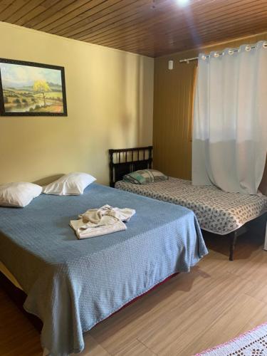 two beds in a room with a blue blanket on it at Pousada avenida in Urubici