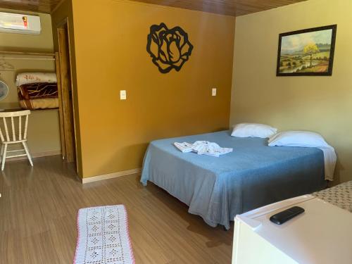 a room with a bed with a blue bedspread at Pousada avenida in Urubici