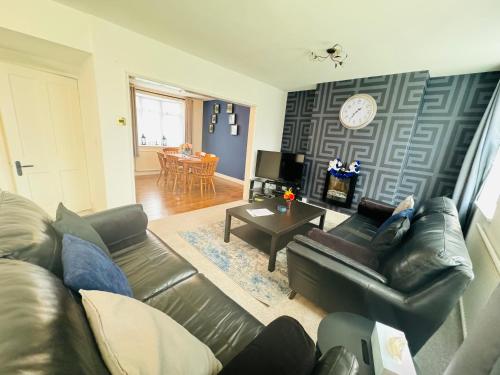 a living room with a leather couch and a table at Chic 5 Bedroom House with Private Parking & Garden in Bristol