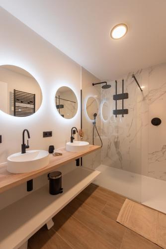a bathroom with two sinks and two mirrors at NIEUW De Grenspaal NOORD 6P - 3SLPK 5 min Maastricht - SAUNA - LAADPAAL in Riemst
