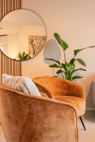 an orange chair in a living room with a mirror at NIEUW De Grenspaal NOORD 6P - 3SLPK 5 min Maastricht - SAUNA - LAADPAAL in Riemst
