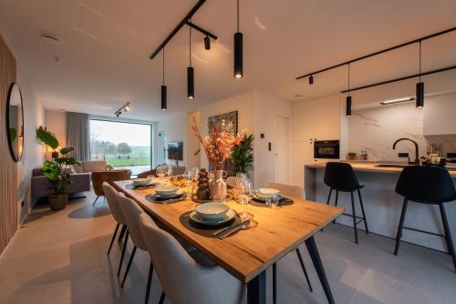 una sala da pranzo e una cucina con tavolo e sedie in legno di NIEUW De Grenspaal NOORD 6P - 3SLPK 5 min Maastricht - SAUNA - LAADPAAL a Riemst