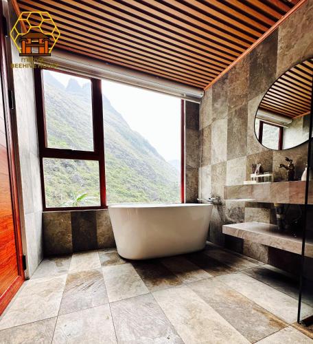 a bathroom with a tub and a large window at Mèo Vạc Beehive House in Mèo Vạc