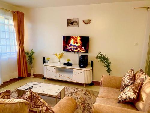 ein Wohnzimmer mit einem Sofa und einem TV an der Wand in der Unterkunft Serenity World in Nairobi
