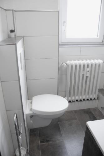 ein weißes Bad mit einem WC und einem Heizkörper in der Unterkunft Modernes Apartment 3 in Bad Kreuznach mit einfachem Self-Check-in in Bad Kreuznach