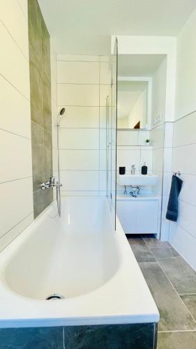 a white bathroom with a tub and a sink at Modernes Apartment 3 in Bad Kreuznach mit einfachem Self-Check-in in Bad Kreuznach