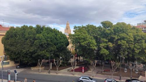 a building with a clock tower in the middle of trees at Pension Segura in Murcia