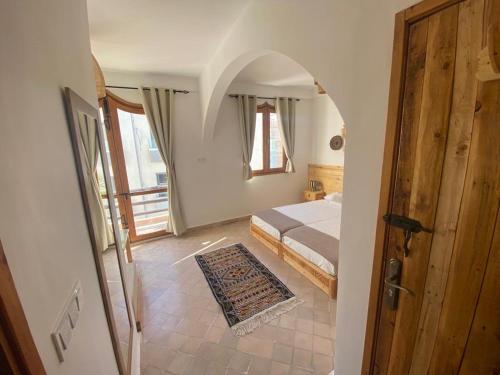 Tamraght OuzdarにあるMAKTUB SURF HOUSEのベッドルーム1室(ベッド1台付)、ドア付きのベッドルーム1室が備わります。