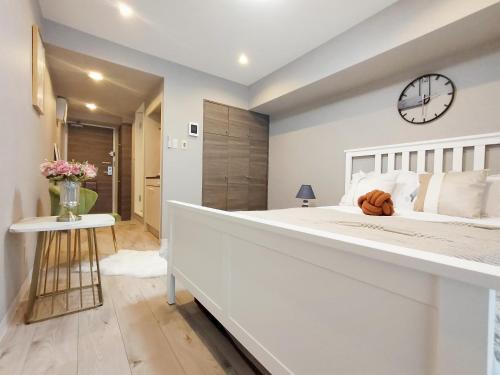 a large white bedroom with a large bed and a clock at S22新宿最中心 東新宿站5分-Shinjuku center 5 mins to Station, Max 3P 直达直达新宿 涉谷 表参道 池袋 上野 代代木 银座 原宿 in Tokyo