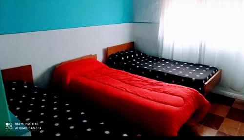1 dormitorio con 2 camas y manta roja en El Descanso! en Carhué