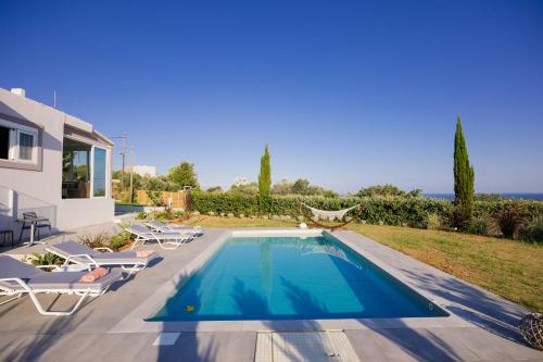 a villa with a swimming pool and lounge chairs at Olive Garden Residence in Platanes