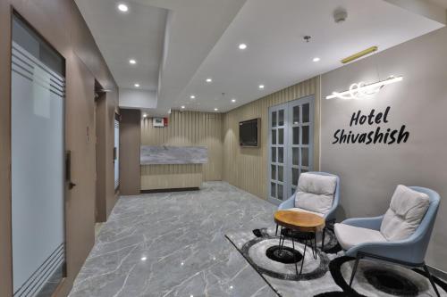 a hospital lobby with two chairs and a sign on the wall at Hotel Shivashish in Ahmedabad