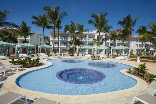 una piscina en el complejo con sillas y sombrillas en Bahia Principe Luxury Esmeralda All Inclusive - Newly Renovated, en Punta Cana