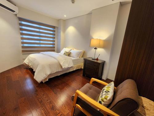 a bedroom with a bed and a couch and a window at Tambuli Seaside Residences Private Hosting Tower D Condominium in Lapu Lapu City