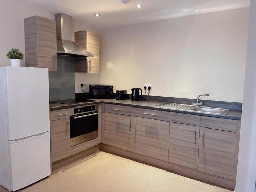 a kitchen with a white refrigerator and a sink at GALAXY APARTMENT in Stockport