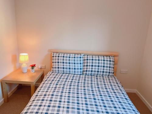 1 dormitorio con 1 cama con colcha azul y blanco a cuadros en GALAXY APARTMENT, en Stockport