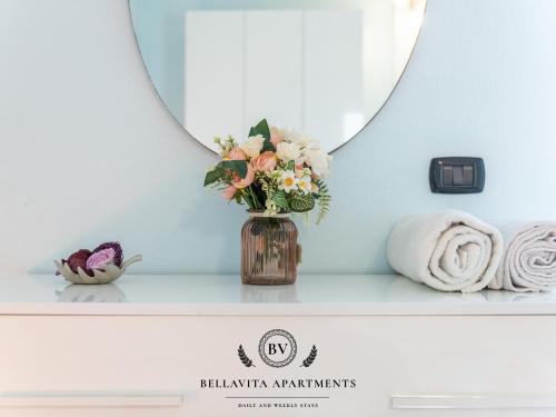 a vase of flowers sitting on a shelf in a bathroom at BellaVita Apartments in Assemini