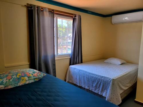 a small bedroom with two beds and a window at Hotel Caribbean Inn in West End