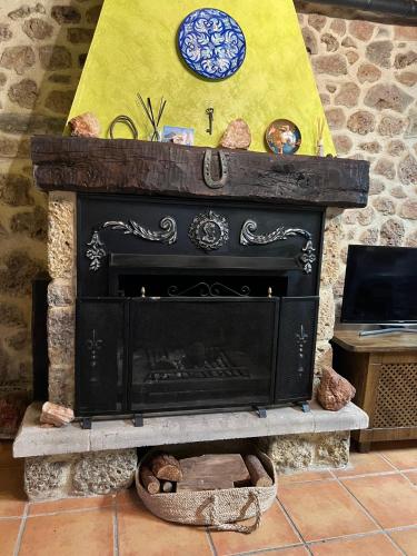 a black fireplace with a clock on top of it at La Casa de Fefita (Stone house in a privileged environment 35 km from Bilbao) in Villanueva de Mena