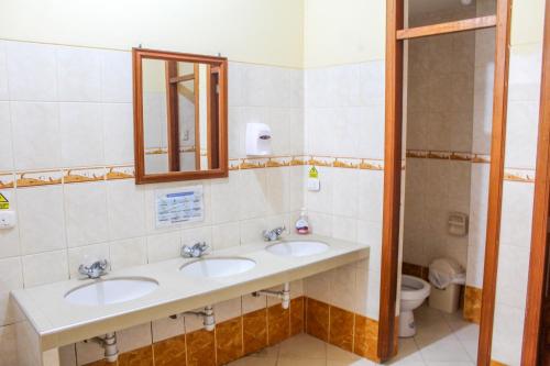 a bathroom with two sinks and a mirror and a toilet at Hotel Los andes Suite Cajamarca in Cajamarca