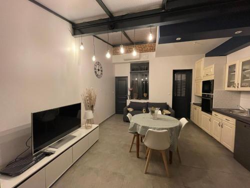 a kitchen and living room with a table and a tv at Le Secret d'Agathe in Amiens