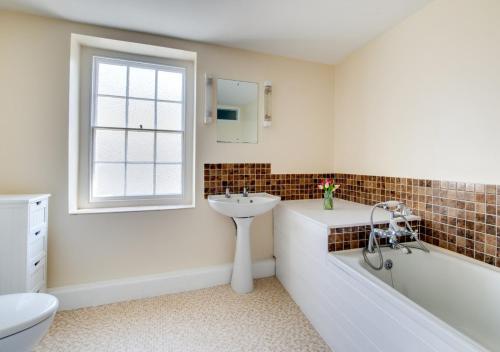 ein Badezimmer mit einer Badewanne, einem Waschbecken und einem WC in der Unterkunft Bell Haven in Swanage