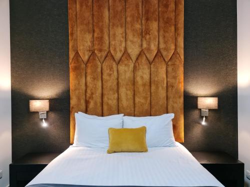 a bed with a wooden headboard and a yellow pillow at VCity ApartHotels Glasgow Central in Glasgow