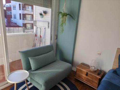 - un salon avec une chaise verte et une fenêtre dans l'établissement Apartamento confort urzaiz vigo., à Vigo