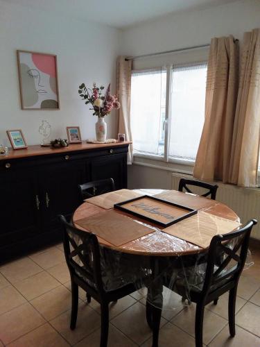 une table à manger avec des chaises et un vase de fleurs dans l'établissement Le Dalton, à Boulogne-sur-Mer