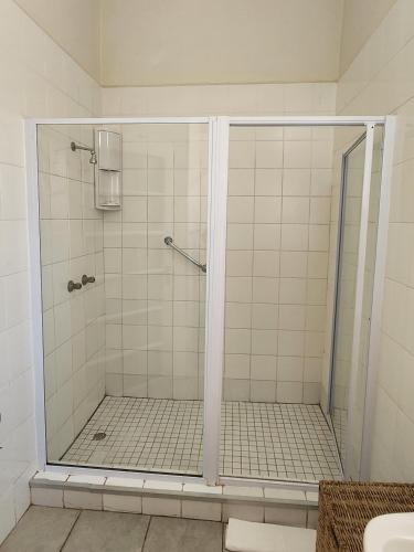 a shower with a glass door in a bathroom at Country Village in Graaff-Reinet