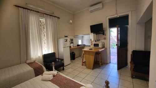een kamer met een bed, een bureau en een keuken bij Country Village in Graaff-Reinet