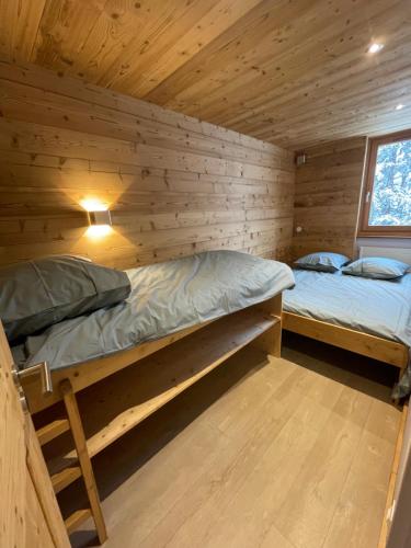 two beds in a cabin with wooden walls at Résidence LE ROC SABAL - Courchevel 1650 in Courchevel