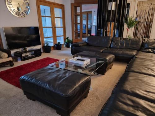 a living room with a leather couch and a coffee table at Entire Spacious 4 Bedroom Zen House with Garden View in Bromley