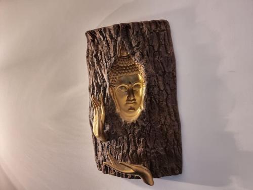 a gold mask hanging on a tree stump at Entire Spacious 4 Bedroom Zen House with Garden View in Bromley