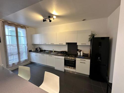 a kitchen with white cabinets and a black refrigerator at Appartement T3 centre ville in Perpignan