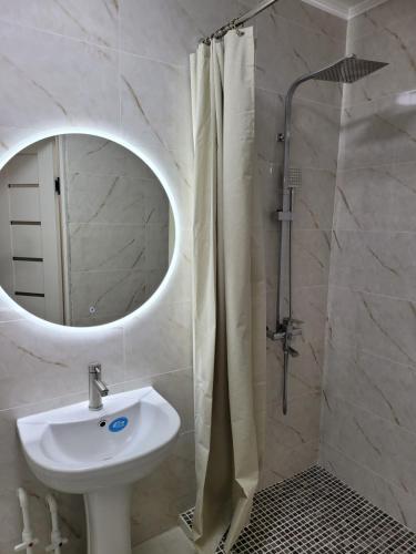 y baño con lavabo y ducha con espejo. en Апартаменты посуточно, en Temirtaū