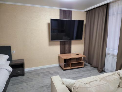 sala de estar con sofá y TV de pantalla plana en Апартаменты посуточно, en Temirtaū