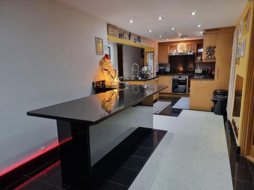 a large kitchen with a large black counter top at Entire Spacious 4 Bedroom Zen House with Garden View in Bromley