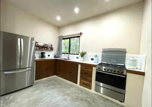 a kitchen with a stove and a refrigerator at Keiki House in Akumal