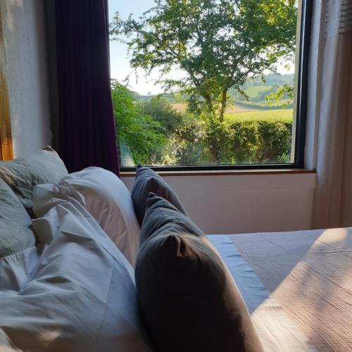 une personne assise sur un lit donnant sur une fenêtre dans l'établissement Rouet Nature, à Tréban