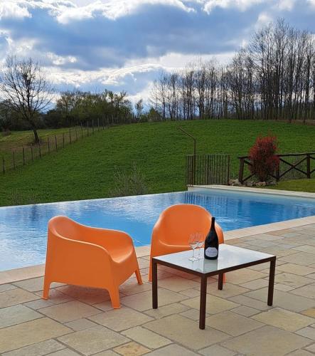 two orange chairs and a table with a wine glass at L'Antico Cipresso in Poppi